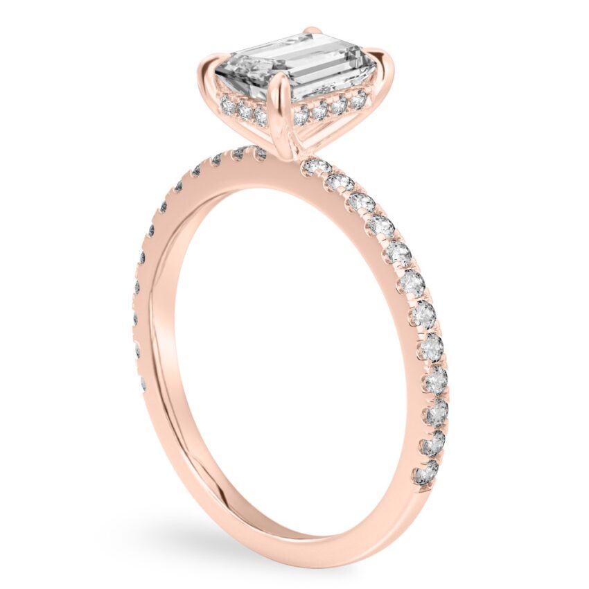Angle view of emerald cut diamond delicate pave hidden halo engagement ring in rose gold