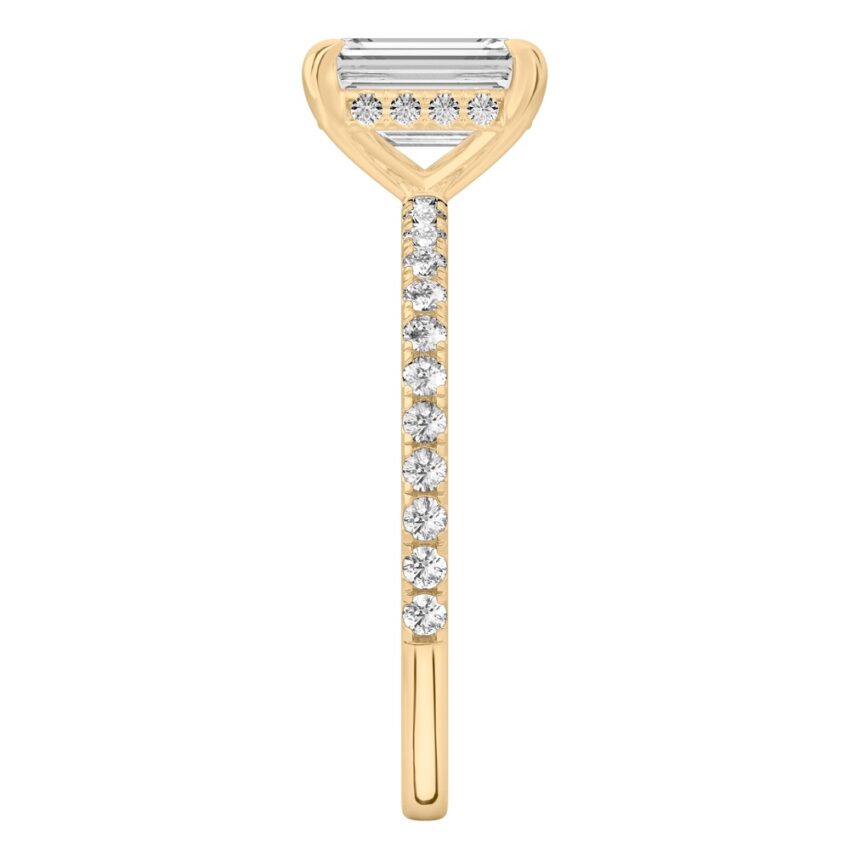Side view of emerald cut diamond delicate pave hidden halo engagement ring in yellow gold
