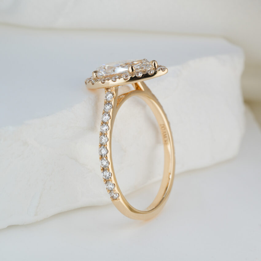 Angle view of 1.50 carat pear cut diamond cushion halo engagement ring in yellow gold lifestyle