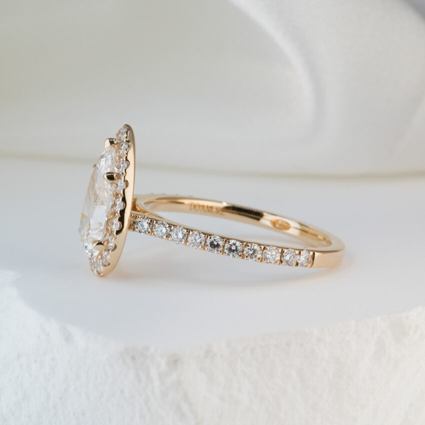 Side view of 1.50 carat pear cut diamond cushion halo engagement ring in yellow gold lifestyle