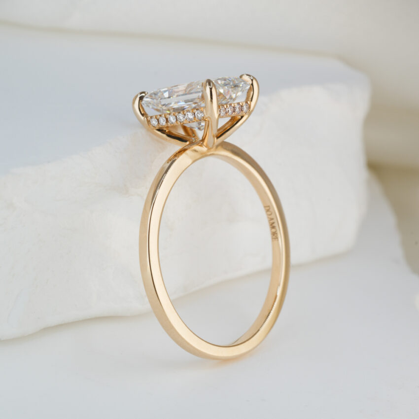 Angle view of 2.43 carat radiant cut diamond ultra low hidden halo engagement ring in yellow gold lifestyle