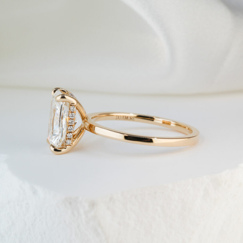 Side view of 2.43 carat radiant cut diamond ultra low hidden halo engagement ring in yellow gold lifestyle