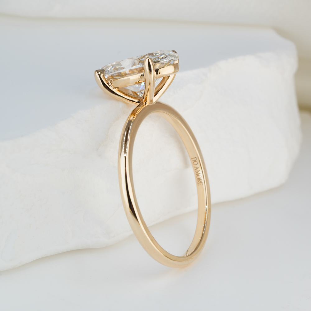 Angle view of 2.51 carat oval cut diamond delicate solitaire engagement ring in yellow gold lifestyle