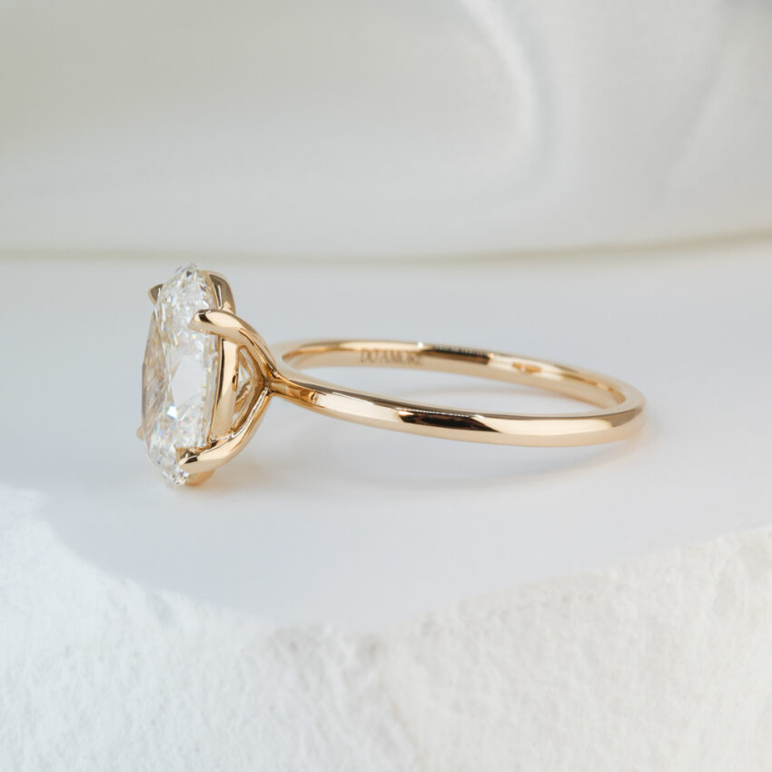 Side view of 2.51 carat oval cut diamond delicate solitaire engagement ring in yellow gold lifestyle