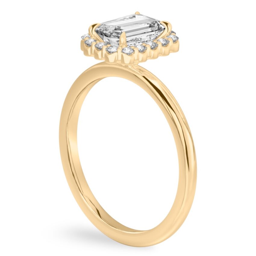 Angle view of emerald cut diamond floral halo engagement ring in yellow gold
