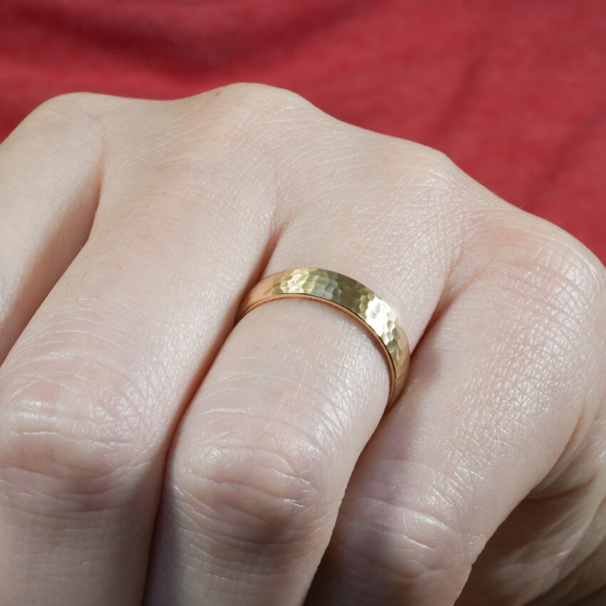 Angle view of domed hammered wedding band in lifestyle