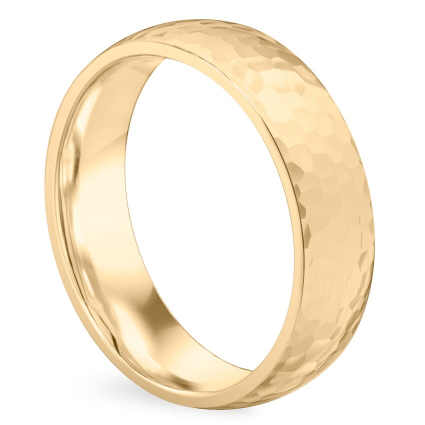 Angle view of domed hammered wedding band in yellow gold